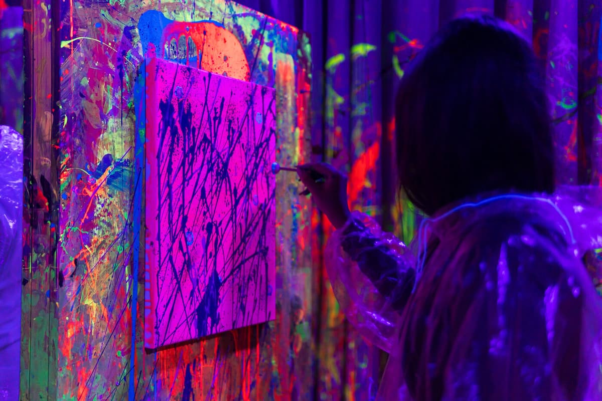 Throwing neon paint at a canvas on the wall